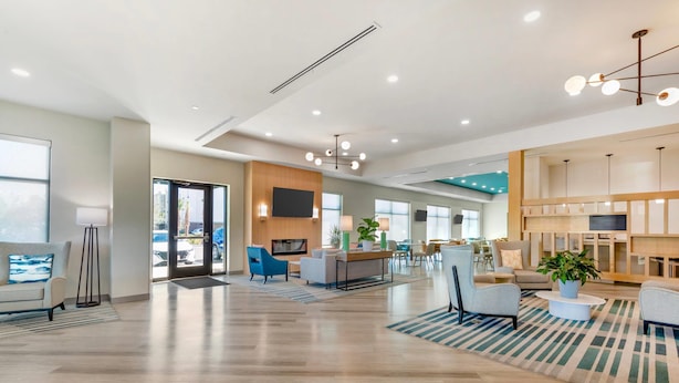 A spacious lobby with a wooden floor, modern furniture, a flat-screen TV, and a large window.