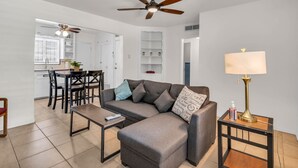 A modern living room with a grey sectional sofa, a coffee table, a side table with a lamp, and a ceiling fan. - Southwest‑Inspired Summer Place | Near UofA (Tucson)