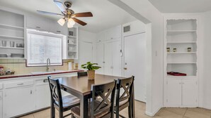 A kitchen with white cabinets, a wooden dining table, and a ceiling fan. - Southwest‑Inspired Summer Place | Near UofA (Tucson)