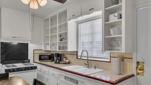 A modern kitchen with white cabinetry, a gas stove, a microwave, and a window with blinds. - Southwest‑Inspired Summer Place | Near UofA (Tucson)
