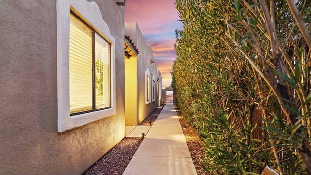 A corridor with a row of rooms, each with a window and a door, leading to a covered outdoor area. - Cozy Summer Oasis | Near UofA & Shows (Tucson)