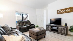 Una sala de estar moderna con un sofá de cuero, un sillón reclinable y un televisor sobre un mueble de madera.