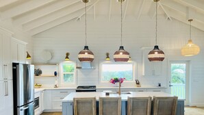 A spacious kitchen with white cabinetry, a large island with bar stools, and pendant lighting.