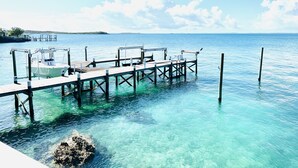 A pier extending into clear turquoise water with a boat docked at the end.