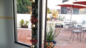 A hotel entrance with a doormat featuring a logo, a window with a view of the patio area, and a Christmas decoration. - HOTEL SANTIAGO (Puebla)