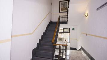 A staircase with a black railing, white walls, and a framed picture above.