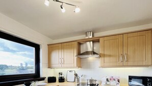 Una cocina moderna con armarios de madera, un horno de acero inoxidable, un microondas y un piso de baldosas negras.