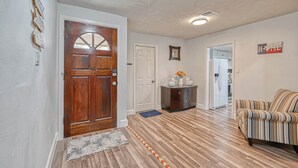 A hallway with wooden flooring, a striped sofa, a wooden door, and a refrigerator in the background. - Spacious 3-bedroom house in beautiful Houston with AC (Houston)