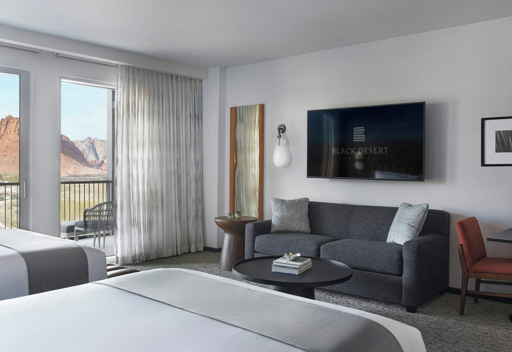 Une chambre d’hôtel avec un lit, un canapé, une table basse, une télévision et une vue sur les montagnes.