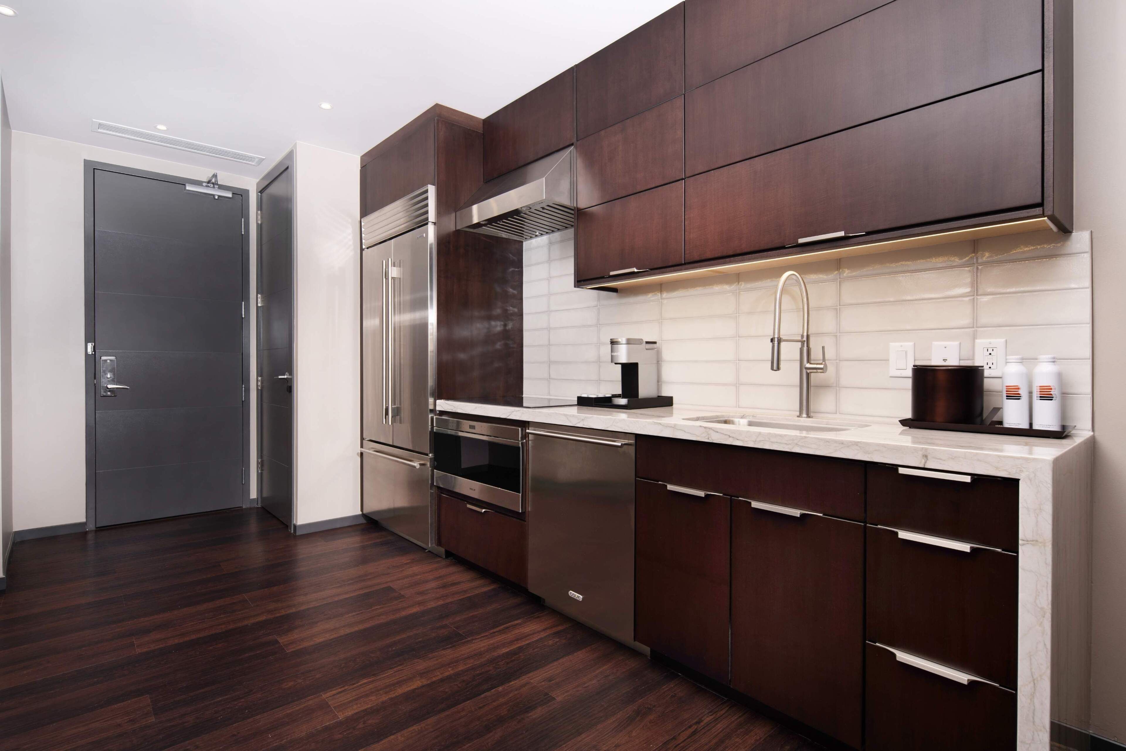 A modern kitchen with dark wood cabinets, stainless steel appliances, and a white tiled backsplash.