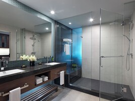 A modern bathroom with a glass shower enclosure, a dark wood vanity, and a large mirror.