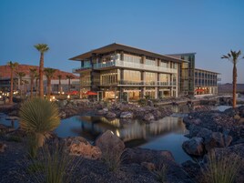 Un hotel moderno con piscina, palmeras y un paisaje desértico al fondo.