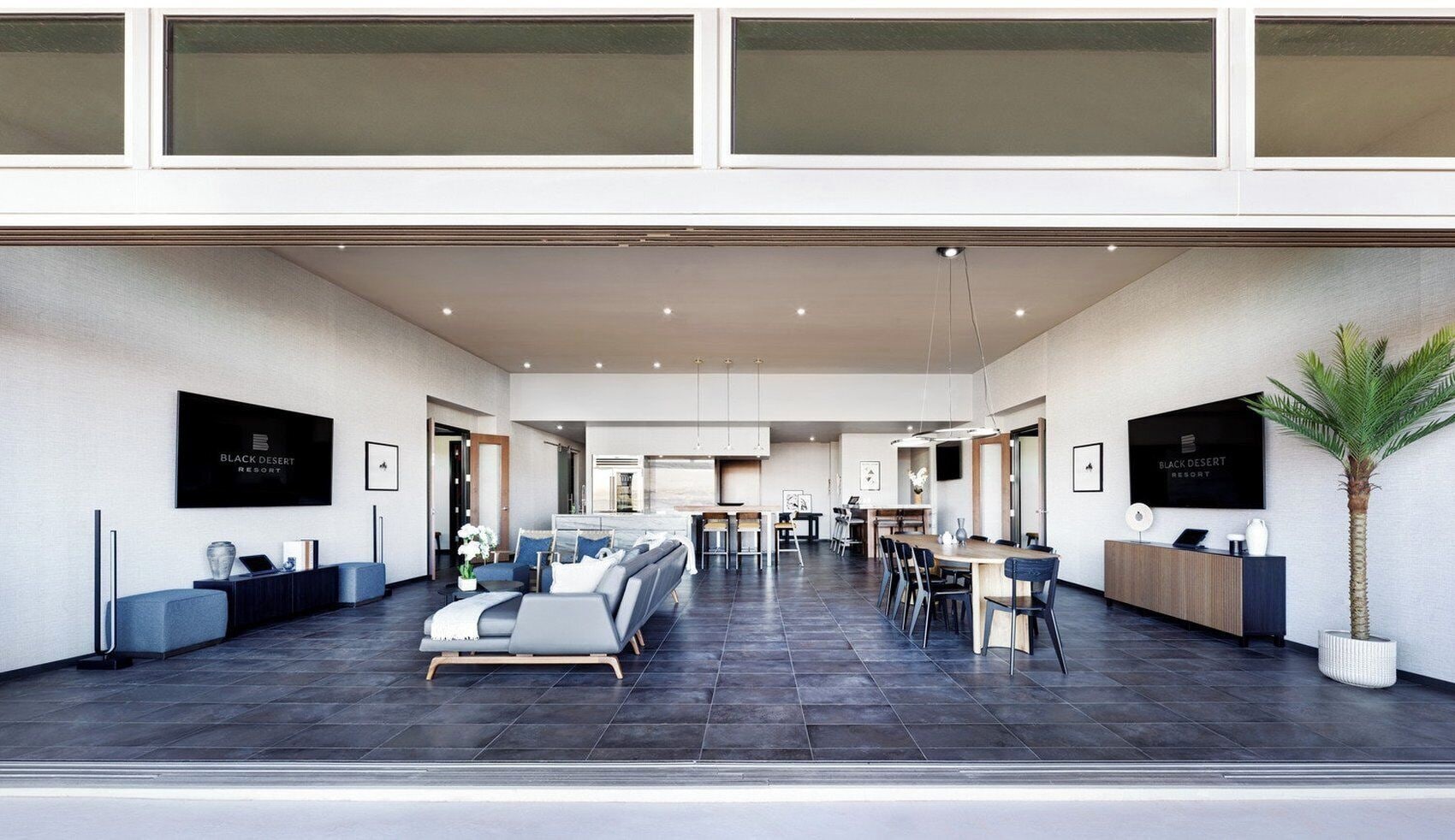 A spacious hotel lobby with a modern design, featuring a seating area, a dining space, and a reception desk.