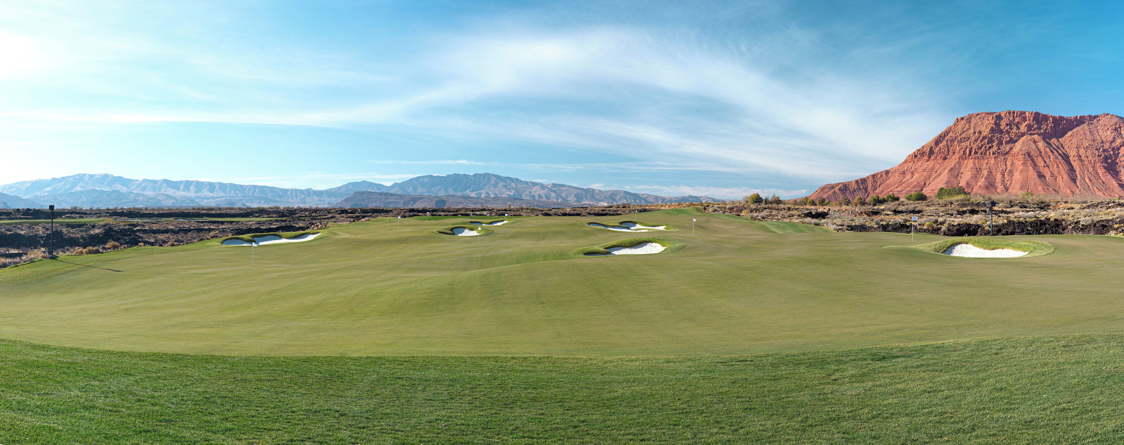 A golf course with bunkers and a mountain in the background.