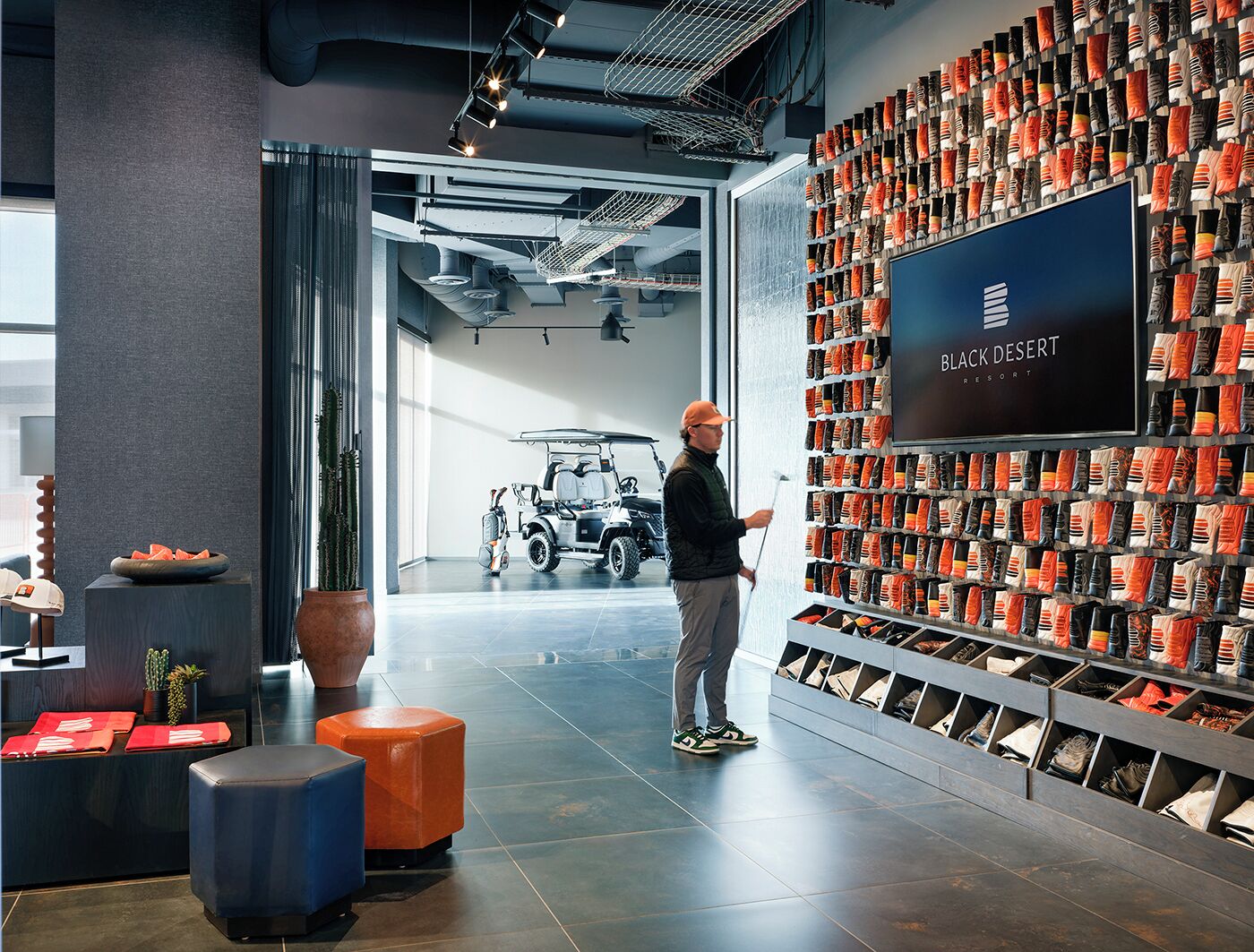 Un interior moderno con una exhibición en la pared de calcetines, un carrito de golf y un letrero que dice "BLACK DESERT RESORT".