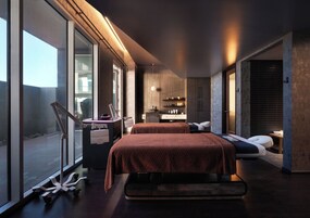 Un dormitorio moderno con una cama grande, un escritorio y vistas amplias por las ventanas.