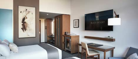 Une chambre d’hôtel avec deux lits, un bureau, une chaise, une télévision et des œuvres d’art accrochées aux murs.