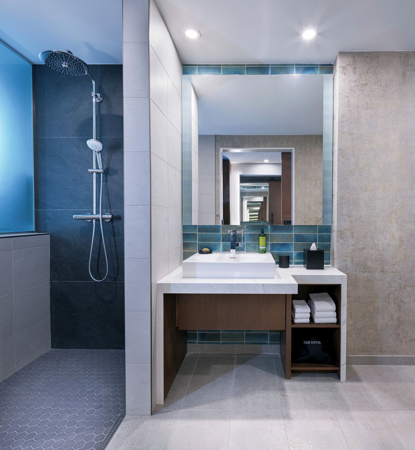 A modern bathroom with a shower, a sink, and a mirror.