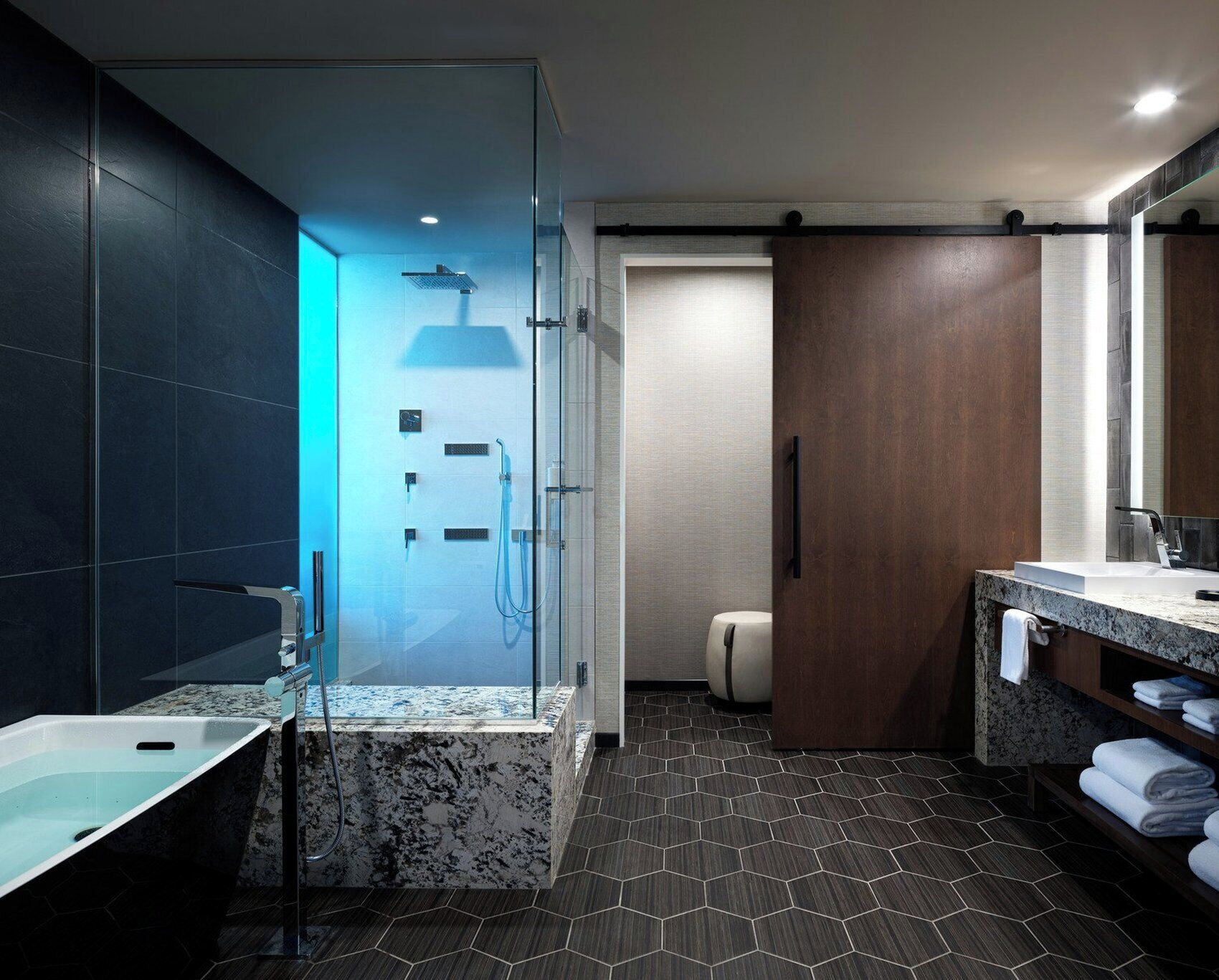A modern bathroom with a glass-enclosed shower, a marble sink, and a wooden vanity.
