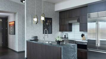 Una cocina moderna con una isla central, electrodomésticos de acero inoxidable e iluminación colgante.