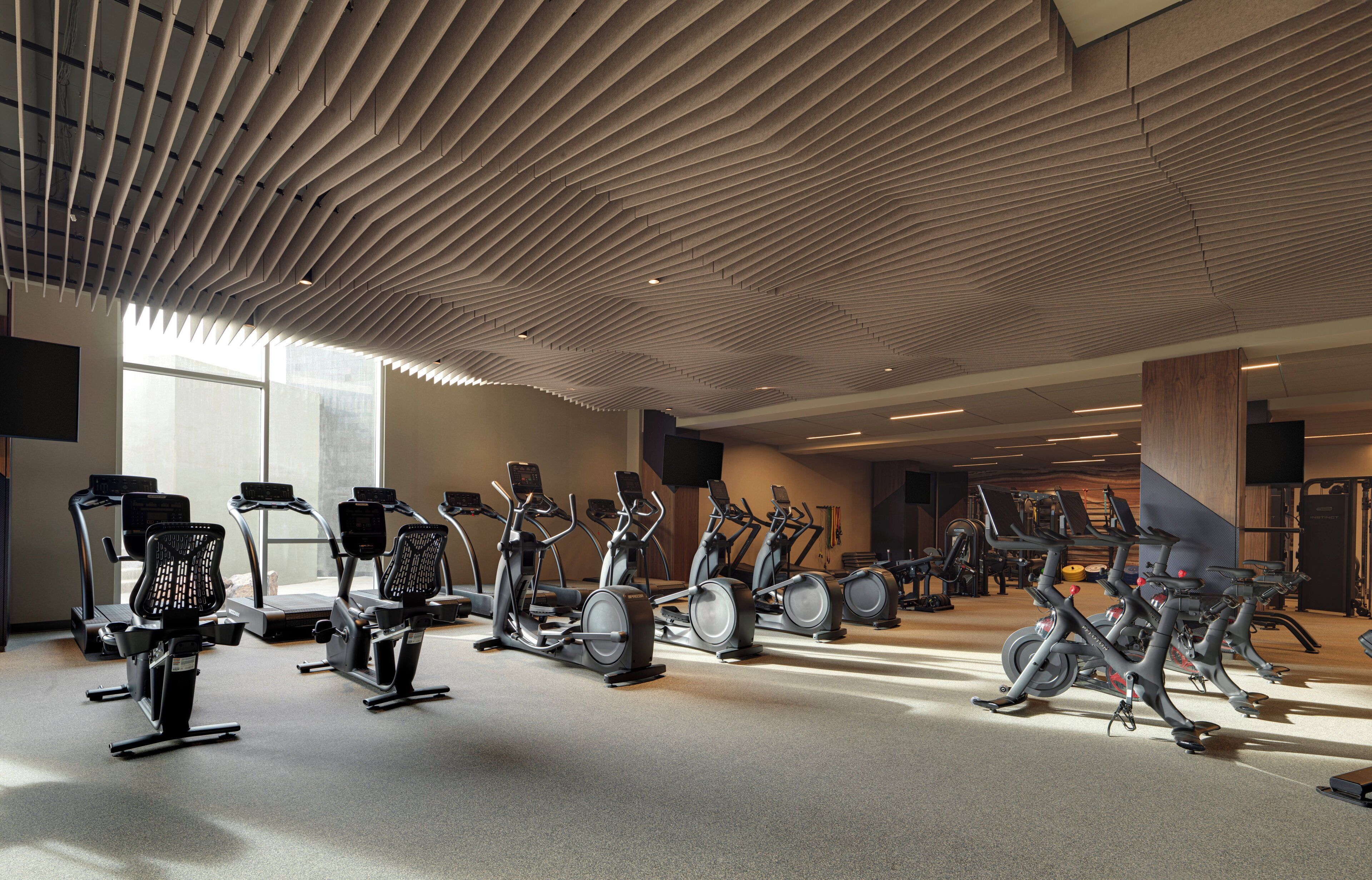 A gym with multiple exercise machines, including treadmills and stationary bikes, arranged in rows.