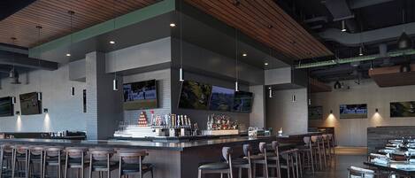 Un moderno bar con una barra larga, varios taburetes y una pantalla de televisión mostrando deportes.