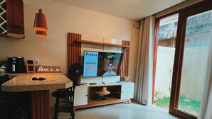 Eine moderne Küche mit Essbereich, einem an der Wand befestigten Fernseher und einem großen Fenster mit Blick ins Freie.