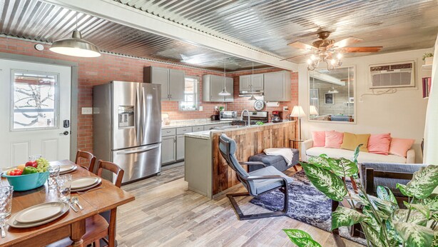 A modern kitchen with stainless steel appliances, a dining area with a wooden table, and a living room with a sofa and plants. - Starlight Vista w/Fire Pit, Grill & Mountain Views (Jasper)