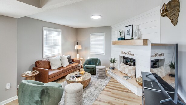 A living room with a brown leather sofa, green armchairs, a coffee table, and a fireplace. - Remote Work Retreat: 3BR w/ Workspace Near KC! (Olathe)