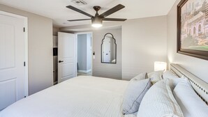 A hotel room with a bed, a ceiling fan, a mirror, and a framed picture on the wall. - Remote Work Retreat: 3BR w/ Workspace Near KC! (Olathe)
