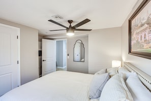 A hotel room with a bed, a ceiling fan, a mirror, and a framed picture on the wall. - Remote Work Retreat: 3BR w/ Workspace Near KC! (Olathe)