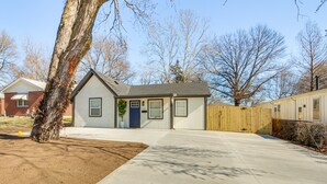 A single-story house with a front yard, a wooden fence, and a tree. - Remote Work Retreat: 3BR w/ Workspace Near KC! (Olathe)