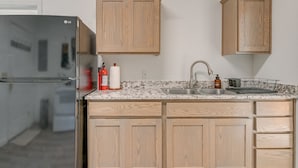 Una cucina con mobili in legno, un lavello in acciaio inox e un frigorifero integrato.