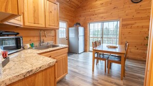 A wooden interior with a kitchen area, granite countertop, and a dining table with chairs. - White Mountains Family Cabin, 4BR and Loft (Bethlehem)