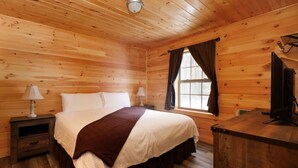 A wooden-paneled bedroom with a bed, two bedside tables with lamps, a dresser, and a window with curtains. - White Mountains Family Cabin, 4BR and Loft (Bethlehem)