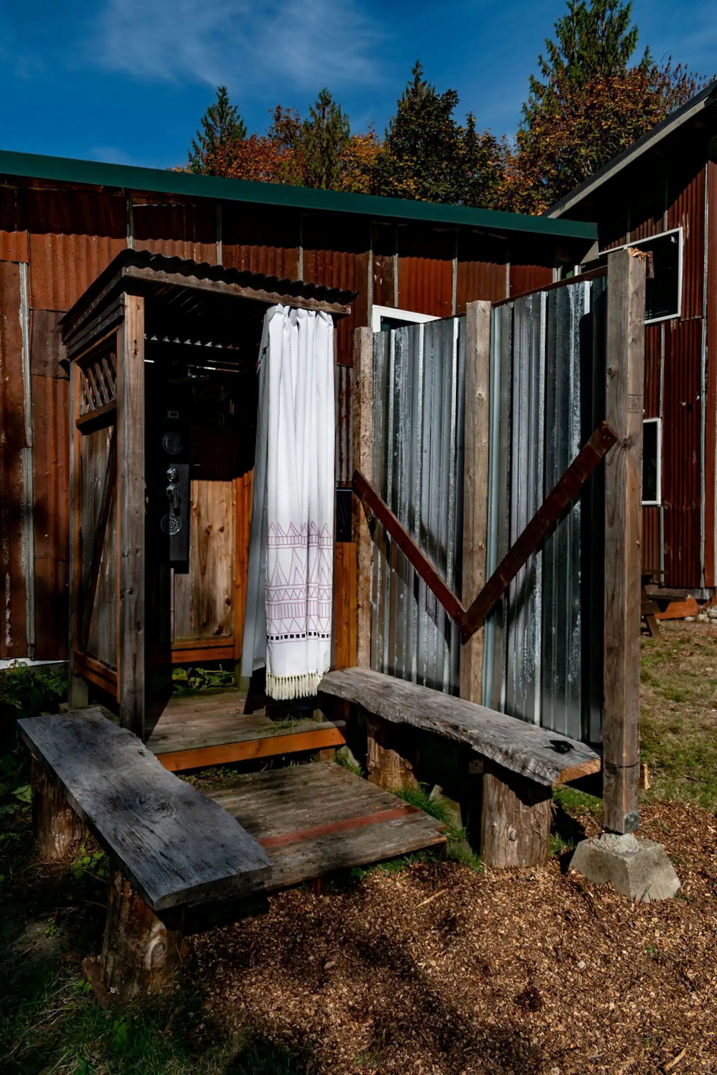 Une structure rustique en bois, dotée d’un banc, d’une porte et d’un petit espace porche.