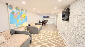 A modern living room with a large world map, a dining area, and a kitchen.