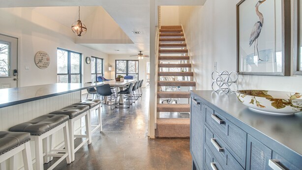 A spacious kitchen with a long counter, bar stools, and a staircase leading to another level. - Deck + Kayaks: Grand Lake of the Cherokees Home (Afton)