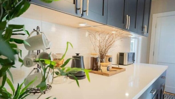 Una cocina moderna con armarios oscuros, una encimera blanca y varios electrodomésticos.