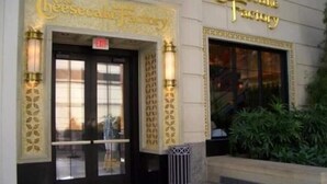 El exterior de The Cheesecake Factory, con una entrada destacada y un letrero sobre la puerta.