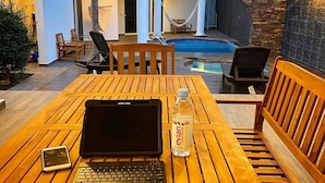 A wooden table with a laptop, a smartphone, and a bottle of Evian water.