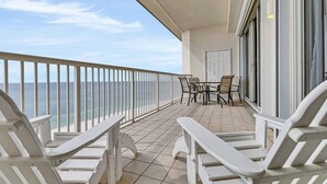 Ein Balkon mit weißen Stühlen und einem Tisch, mit Blick auf das Meer.