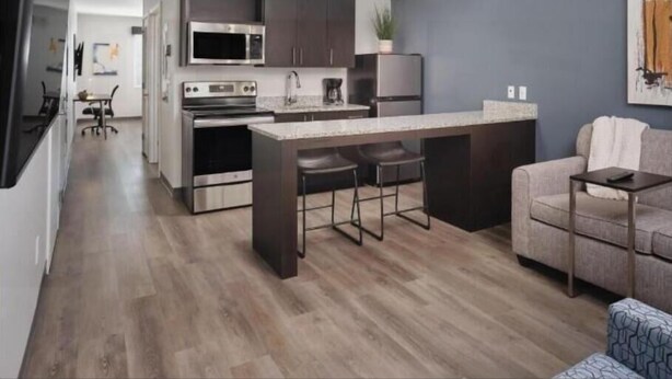 Une cuisine moderne avec des meubles de couleur sombre, des appareils en acier inoxydable et un îlot central doté de tabourets de bar.
