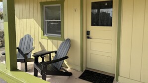 A porch with two Adirondack chairs and a door with a window. - Eastern Sierra Motor lodge (Independence)