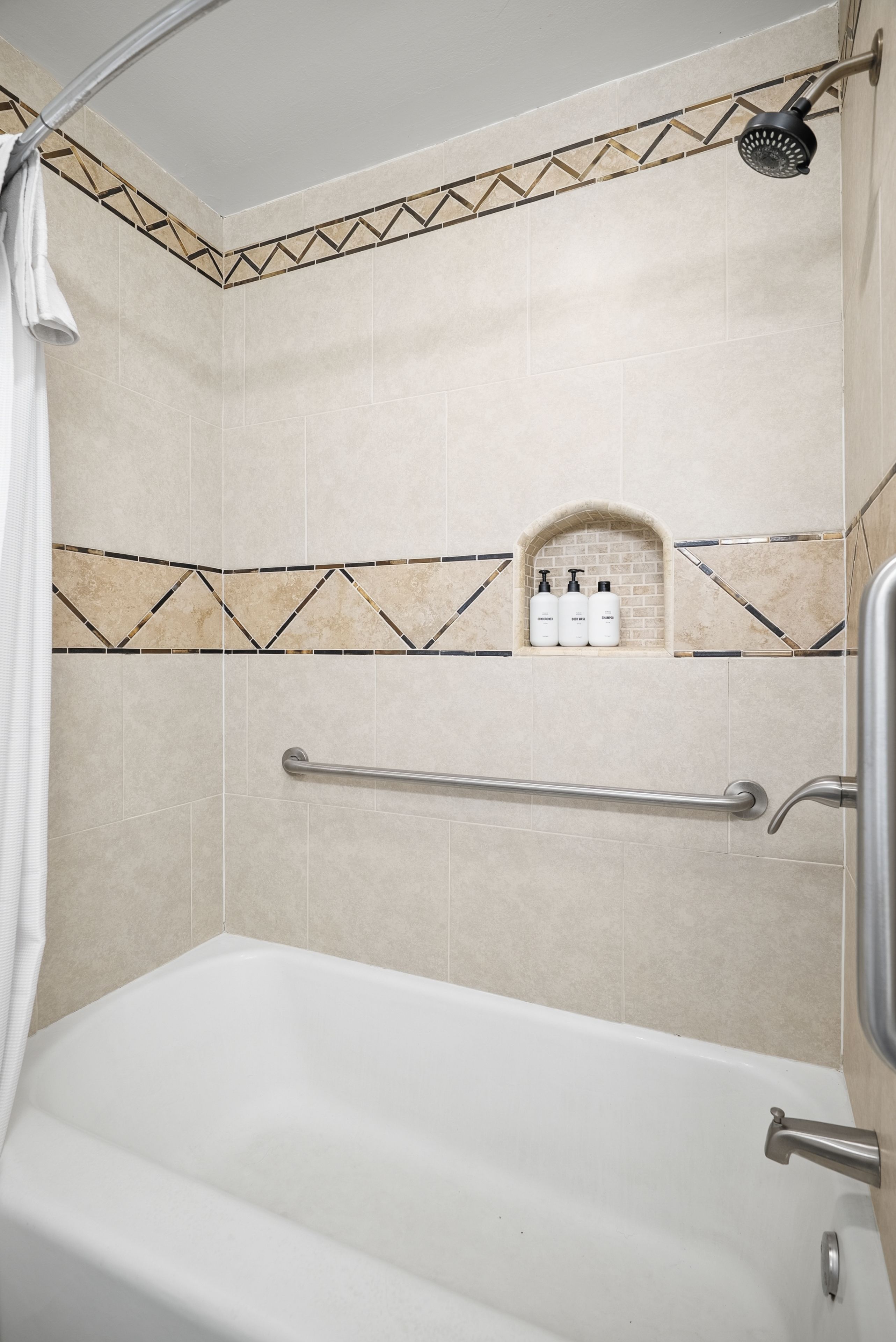 A bathroom with a bathtub, a shower, and a shelf with toiletries.