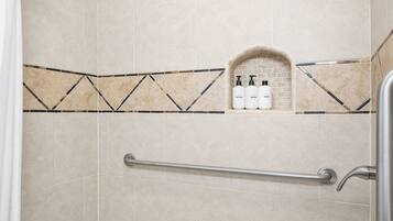 A bathroom with a bathtub, a shower, and a shelf with toiletries.
