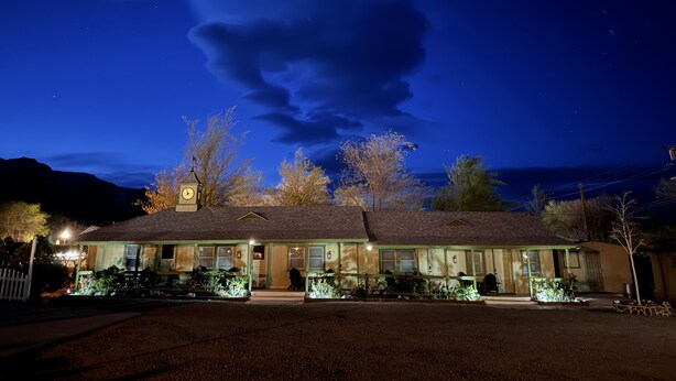 A motel with a clock tower, a covered parking area, and a view of the mountains. - Eastern Sierra Motor lodge (Independence)