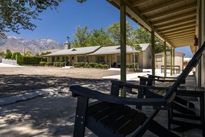 A motel with a covered outdoor seating area, a parking lot, and a mountain backdrop. - Eastern Sierra Motor lodge (Independence)