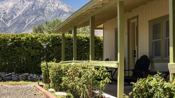 A building with a covered porch, a dining table, and chairs.