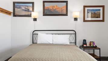 Habitación de hotel con cama, dos lámparas de pared y tres cuadros en la pared.